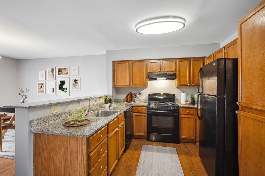 a kitchen with black appliances and wooden cabinets at Villages at Morgan Metro, Landover, MD 20785