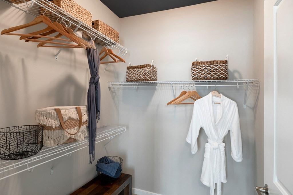 a walk in closet with a white robe hanging on the wall