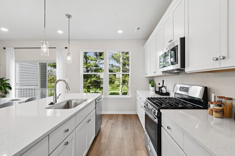 A modern kitchen with white cabinets and a black stove top.