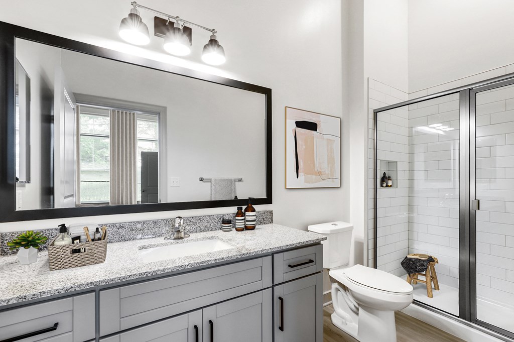 The Forge bathroom with a large mirror and a shower with a glass door