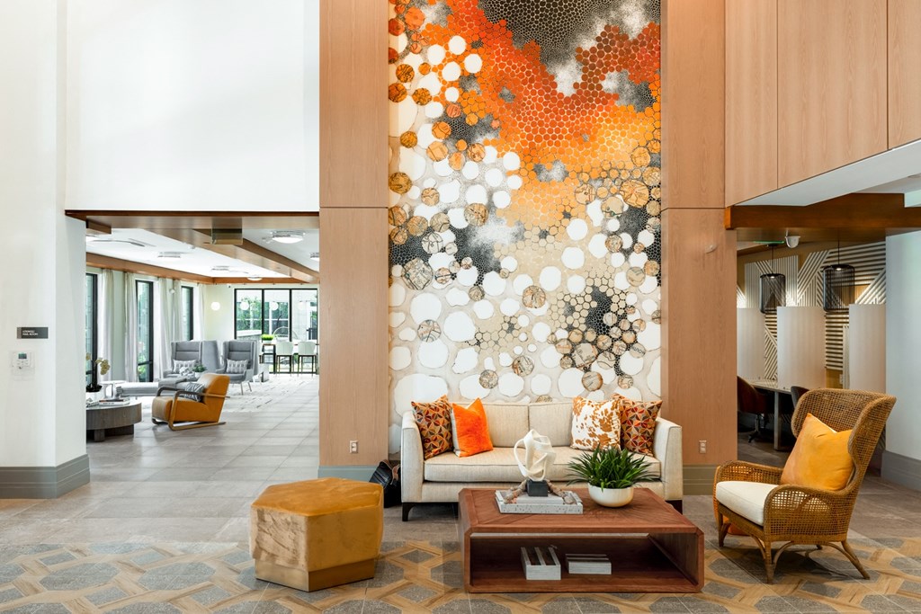 a lobby with a white couch with orange and black pillows and a brown coffee table