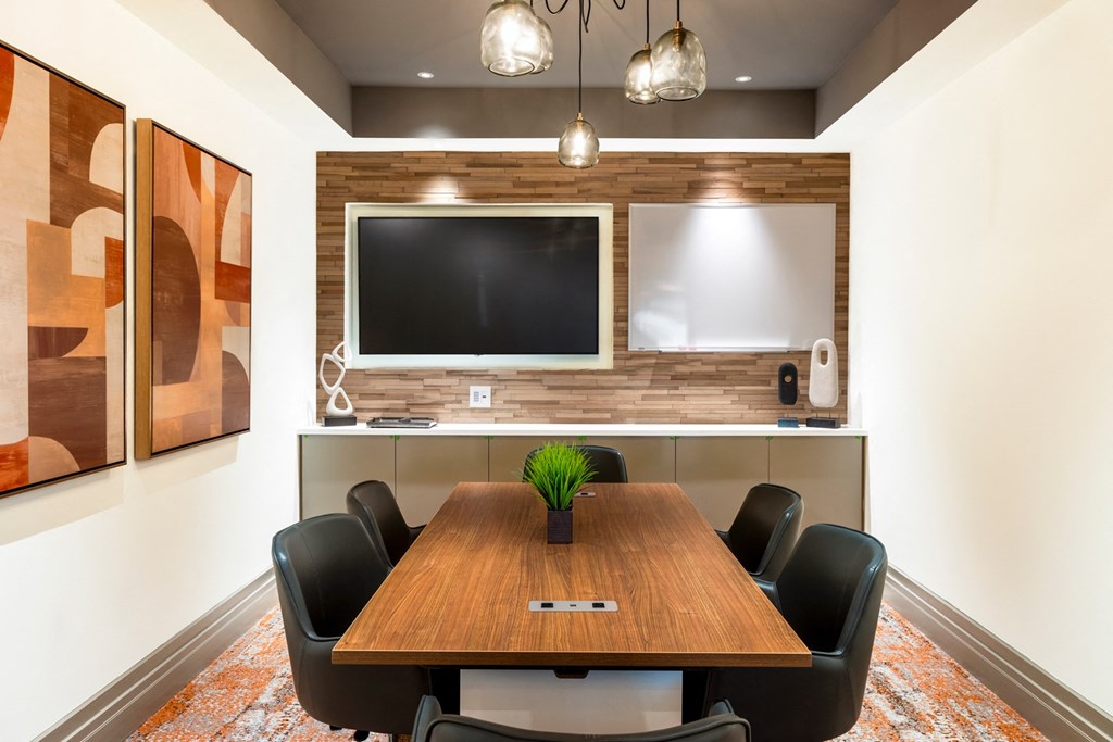 a conference room with a table and chairs and a tv on the wall
