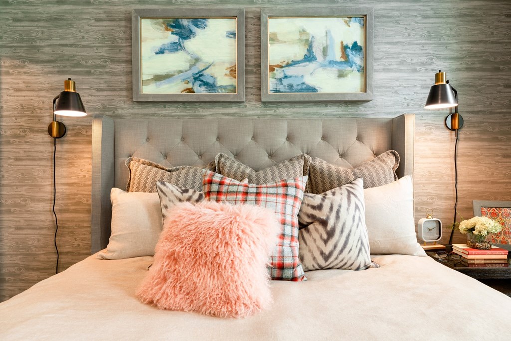 a bedroom with a bed and pillows and two paintings on the wall