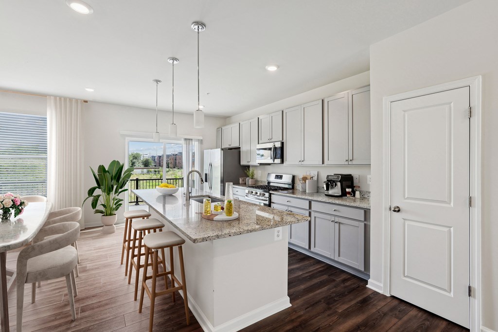 an open kitchen and dining room with white cabinets and a marble counter top an open kitchen and dining room with white cabinets and a marble counter top at Refinery Row, Baltimore, 21224