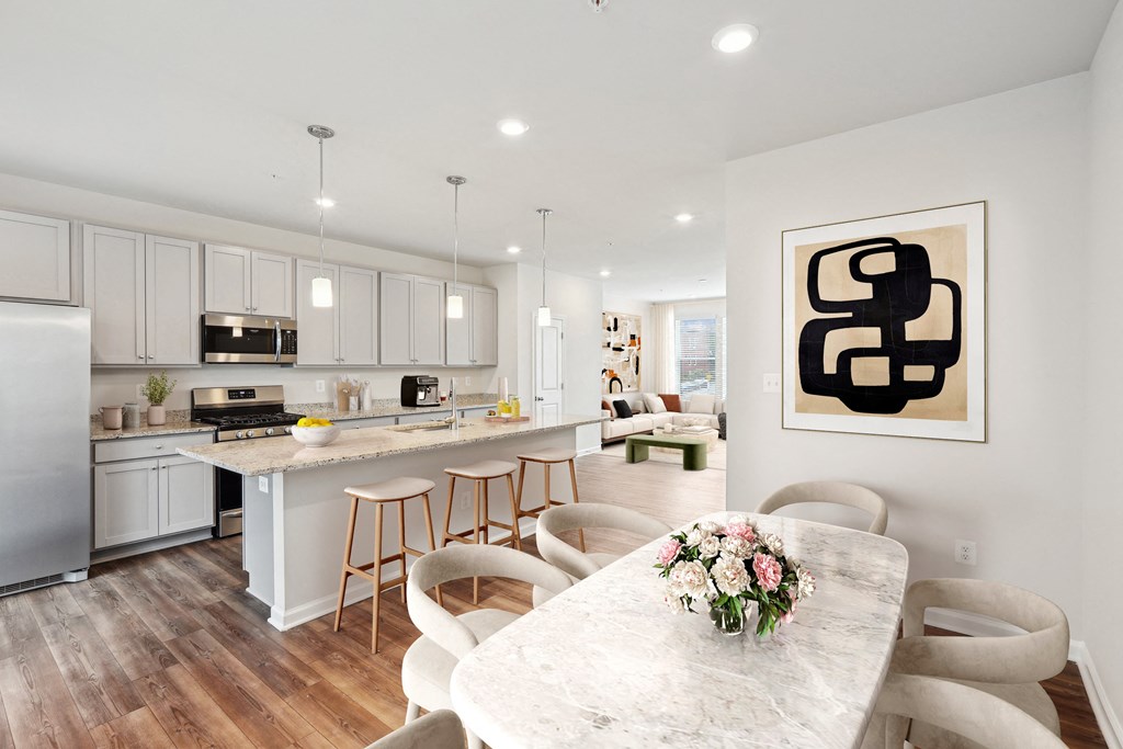 an open kitchen and dining room with white cabinets and a marble table an open kitchen and dining room with white cabinets and a marble table at Refinery Row, Baltimore, MD 21224