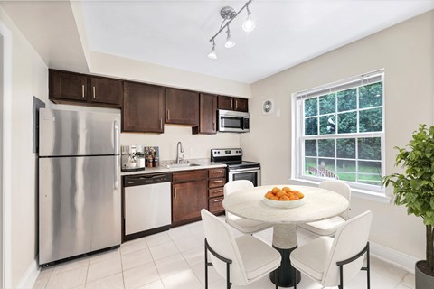 A kitchen with a table and chairs in front of a window.