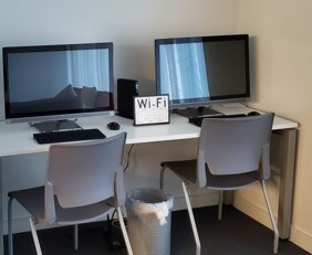 Two computer monitors and a Wi-Fi sign on a desk.
