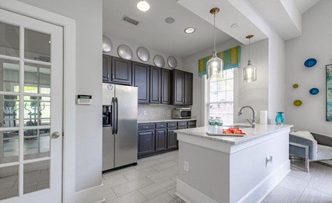 A kitchen with a white island and stainless steel appliances.