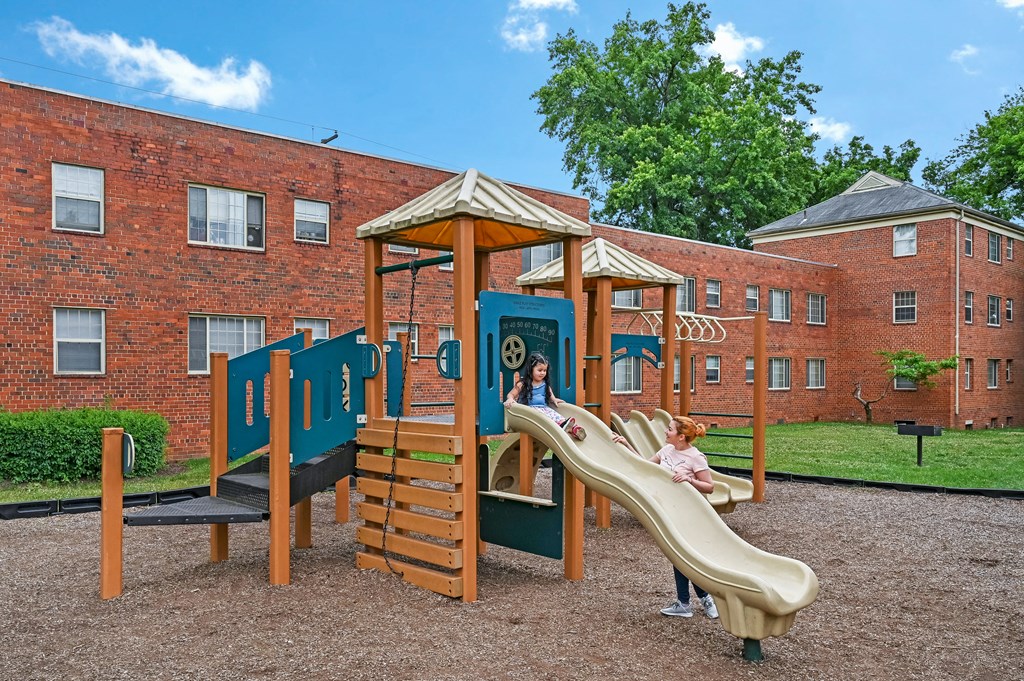 a child playing on a playground in front of a brick building at Hamilton Manor Apartments, Hyattsville, Maryland