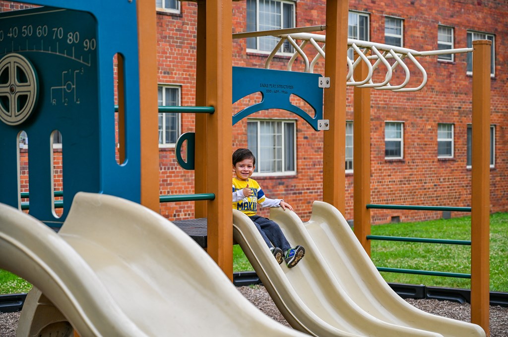 a boy is sitting on a slide on a playground at Hamilton Manor Apartments, Hyattsville, 20782