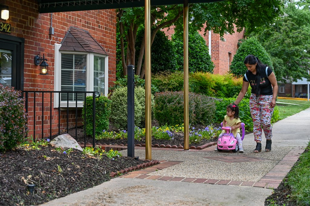 a woman pushing a little girl in a pink toy car at Hamilton Manor Apartments, Hyattsville, MD