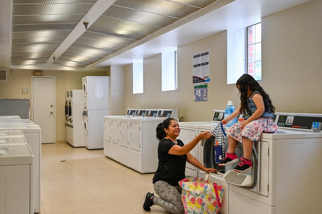 two young girls sitting on washing machines in a laundry room at Hamilton Manor Apartments, Hyattsville, MD 20782