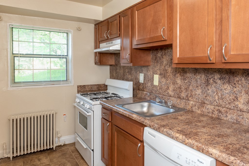 a kitchen with a sink and stove and wooden cabinets at Hamilton Manor Apartments, Maryland