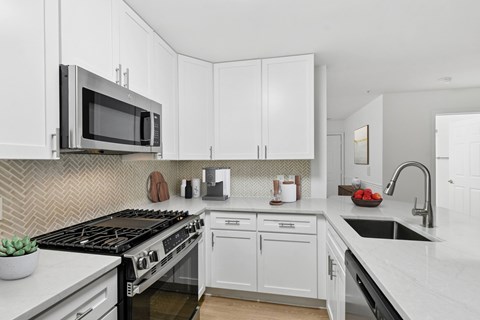 A kitchen with white cabinets and a black stove top.