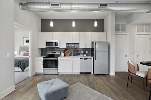 a kitchen and living room with white cabinets and stainless steel appliances
