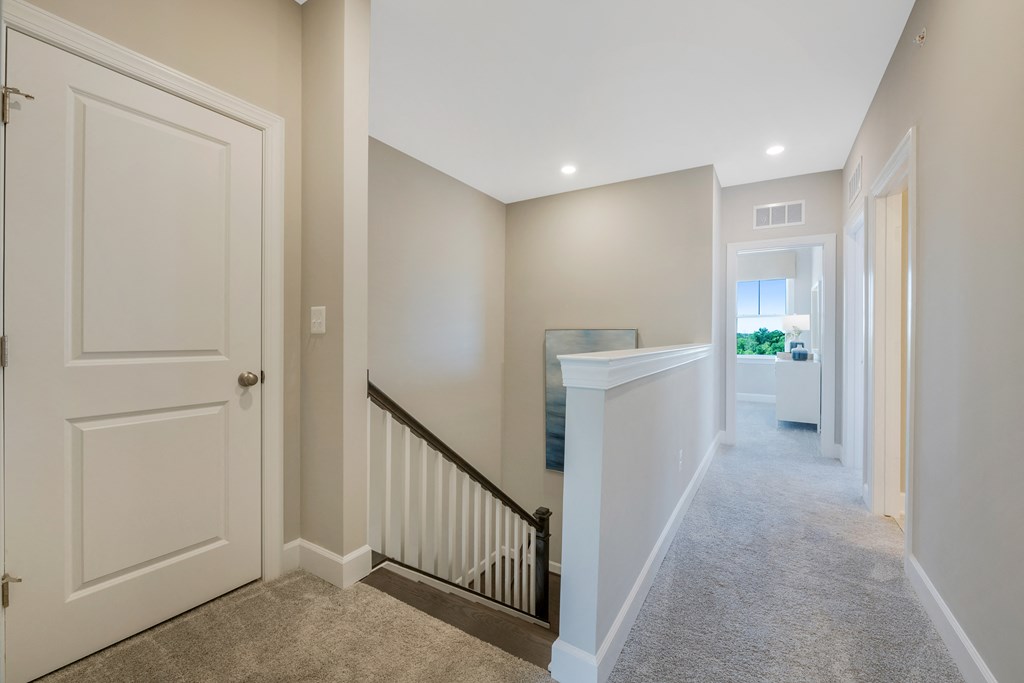 the landing of a home with a staircase and a hallway with white doors