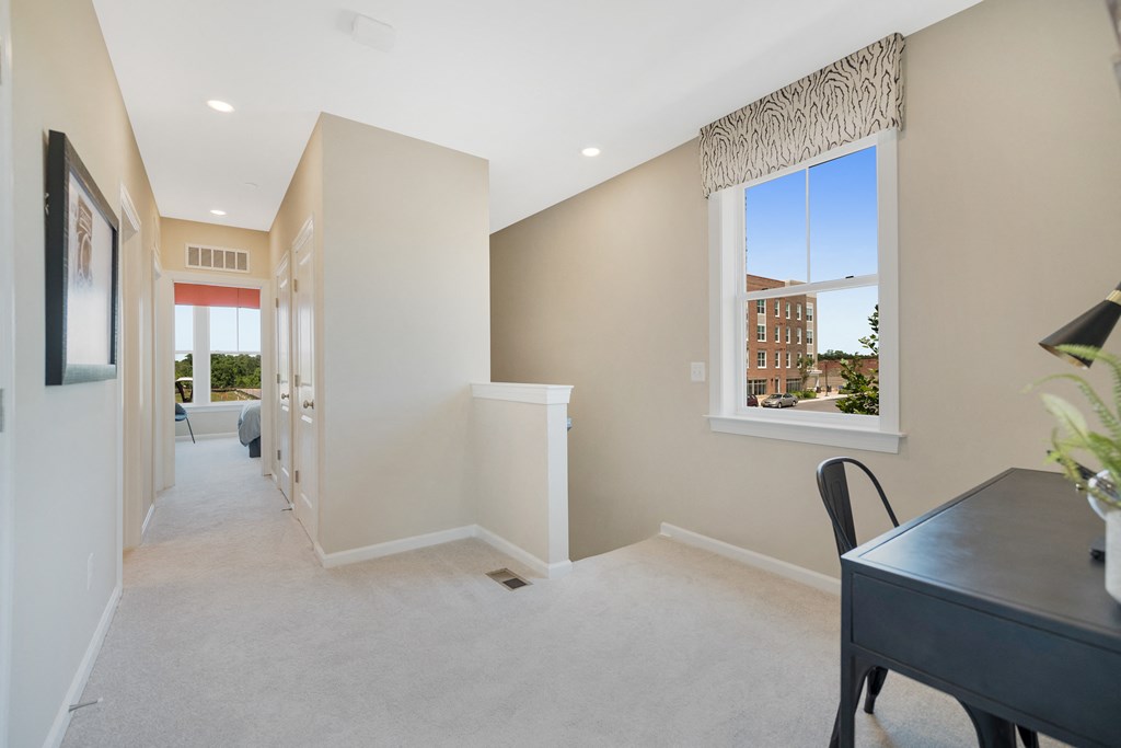 a long hallway with a desk and a window in a house