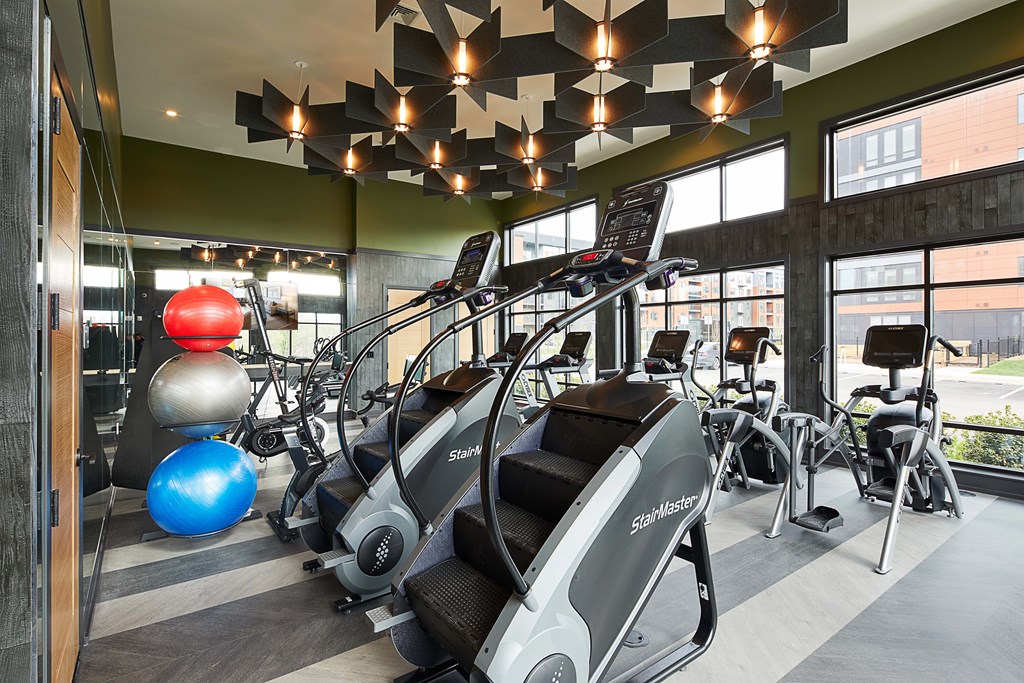 A gym with a variety of equipment including treadmills and exercise balls.