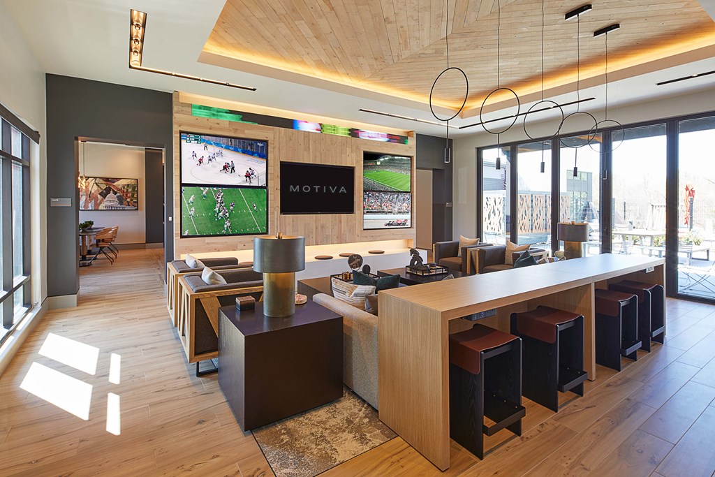 A bar with a long counter and stools is in a room with a wooden floor and ceiling.