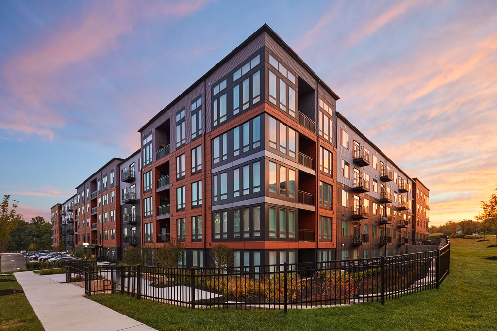 A modern apartment building with a black fence in front.