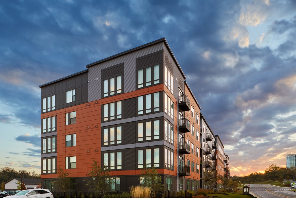 A modern apartment building with a mix of grey and orange panels.