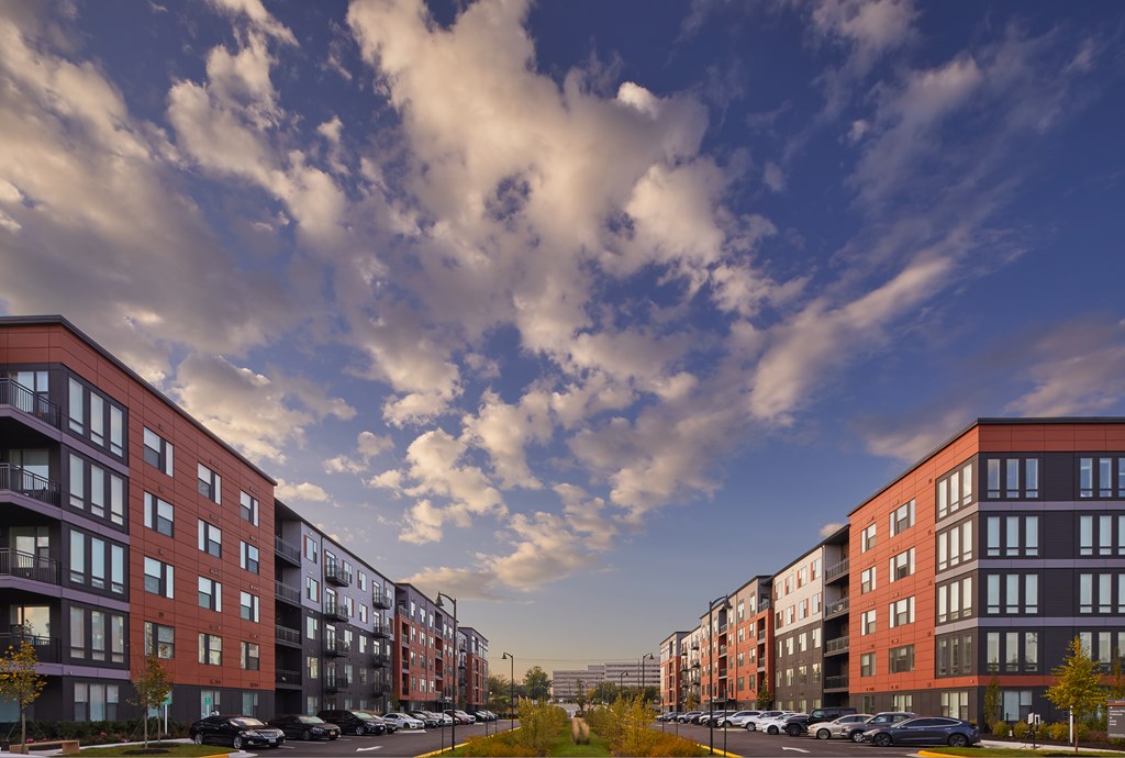 A row of modern apartment buildings with cars parked in front.