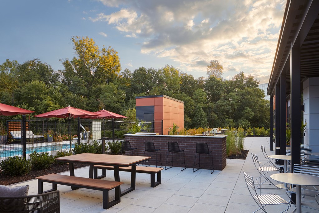 A patio with a table and chairs overlooking a pool.