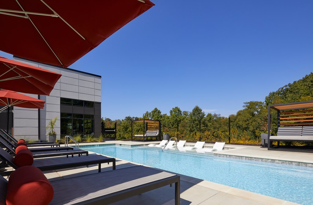 A pool with red chairs and a building in the background.