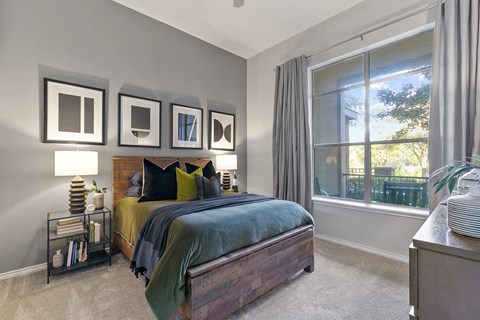 A bedroom with a bed, nightstand, and a window with curtains at Prairie Crossing, Texas