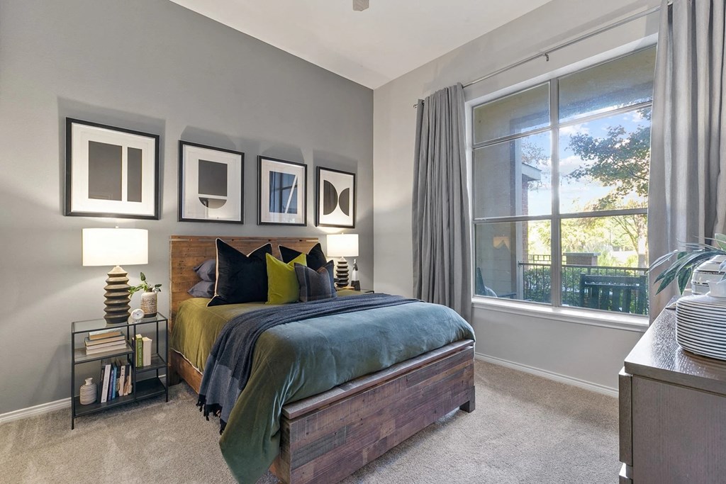 A bedroom with a bed, nightstand, and a window with curtains A bedroom with a bed, nightstand, and a window with curtains at Prairie Crossing, Texas