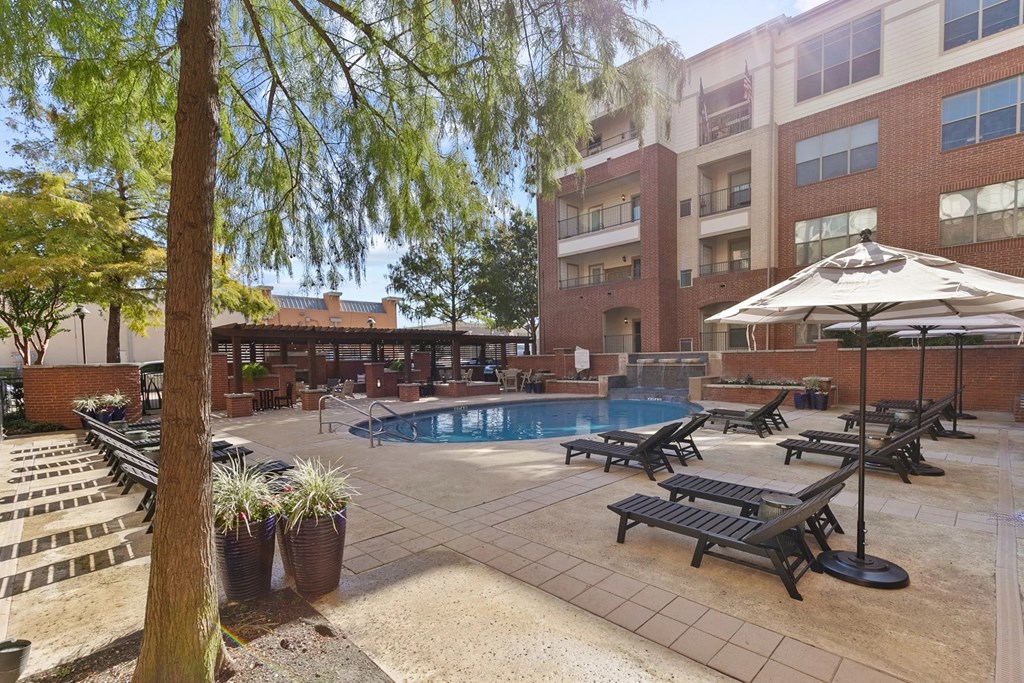 A pool area with sun loungers and a tree at Prairie Crossing, Farmers Branch, 75244