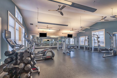 A spacious gym with various exercise equipment and a television mounted on the wall.