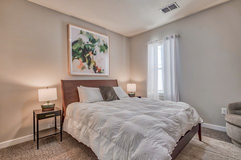 A bedroom with a large bed and a painting above it.