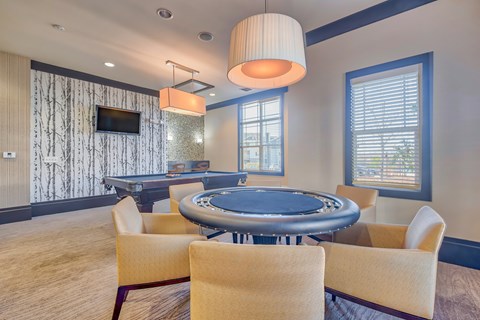 A room with a pool table and chairs.