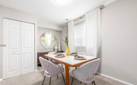 Dining room with round mirror and white table at The Brook At Columbia Apartments, Columbia