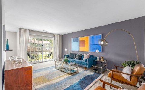 A living room with a blue couch and a wooden chair.