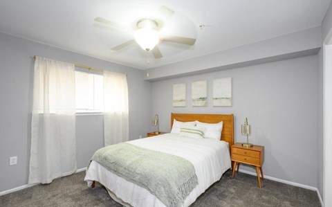 A bedroom with a bed, nightstand, and a ceiling fan.
