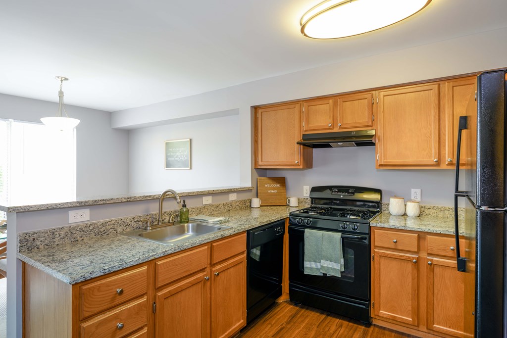 A kitchen with wooden cabinets and a black refrigerator.