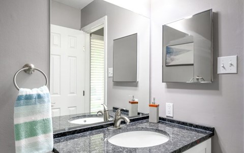 A bathroom with a black granite countertop and a white sink.