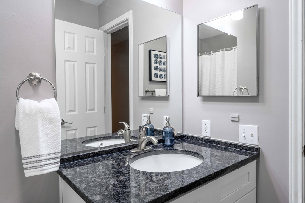 A bathroom with a black granite countertop and a white towel hanging on a towel ring.