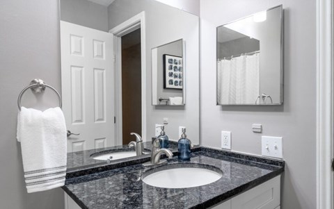 A bathroom with a black granite countertop and a white towel hanging on the towel rack.