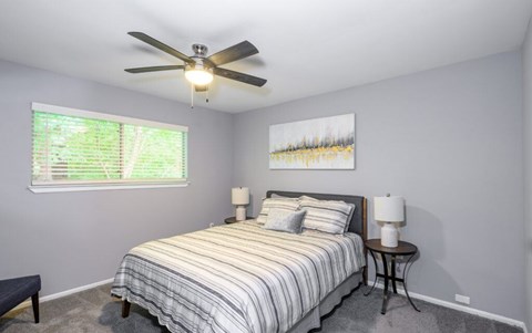 A bedroom with a bed, two lamps, and a painting on the wall.