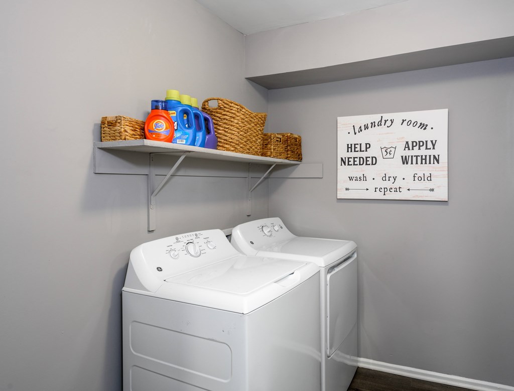 A laundry room with a washer and dryer and a sign on the wall.
