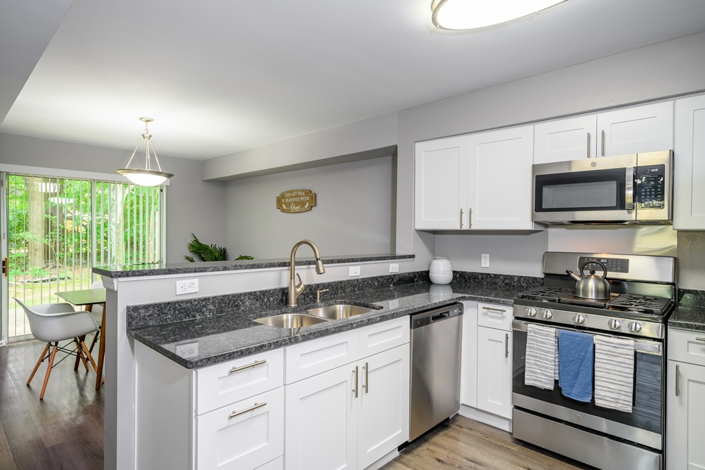 A modern kitchen with white cabinets and a granite countertop.