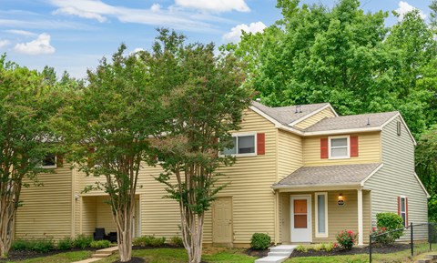 A yellow house with a red door and a small porch.