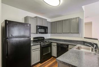 A black refrigerator is in a kitchen with a black stove and black oven at Park at Winterset Apartments, Owings Mills, MD