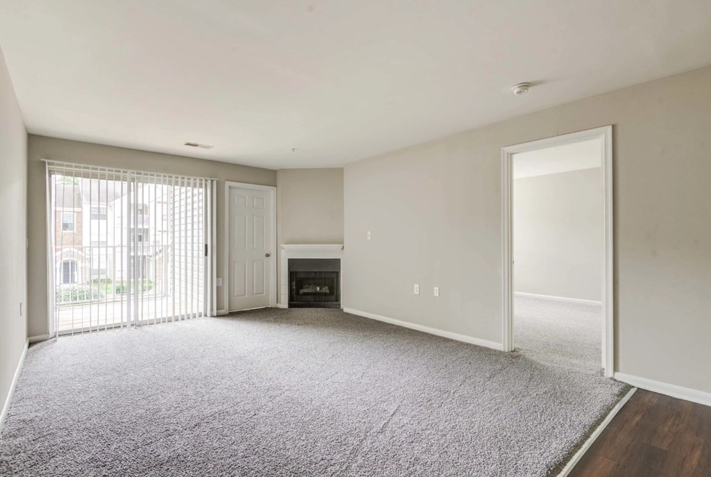 A large, empty room with a fireplace and sliding glass doors at Park at Winterset Apartments, Maryland, 21117
