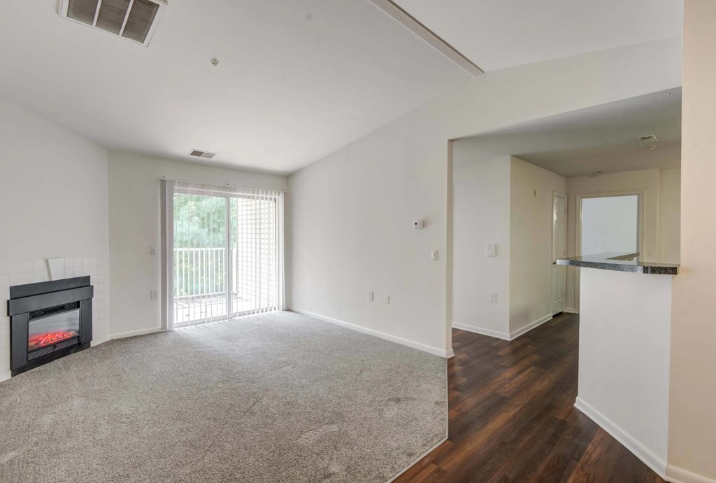 A living room with a fireplace and sliding glass doors at Park at Winterset Apartments, Owings Mills