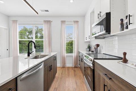 A modern kitchen with white countertops and wooden floors.