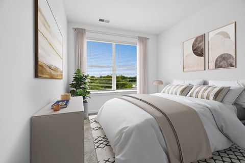 A bedroom with a large bed and a window overlooking a green landscape.